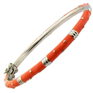 The zirconmania Bracelet Thin Gold tone Enamel Bangle 501B5339 features alternating smooth gold-tone and glossy coral-orange enamel sections with silver dot accents and a clasp. Also available in zirconite black finish.