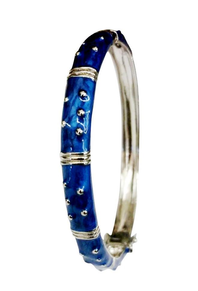 The zirconmania Bracelet Hinged Enamel Bangle 501B41902 features a shiny blue enamel finish, accented with raised silver dots and bands. This silver bangle includes a hinged design and secure safety catch for peace of mind.