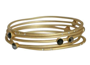 The zirconmania Bracelets Gold Stack-able .622B0102 features multiple overlapping gold bands adorned with small clear and large black gemstones, creating an elegant, stackable bangle style.