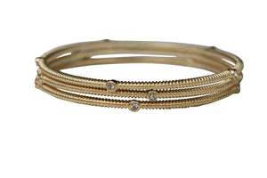 The zirconmania Bracelet Three Designer Bangles 622B0166x3 features three intertwined gold bands adorned with round diamonds and crystal stations, displayed on a plain white background.