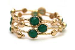 The zirconmania Bracelet Multi-Wire Gold and Beads Bangle 22B0241A showcases stacked gold wires with round green gemstones and small gold beads in an intertwining design, displayed on a white background.