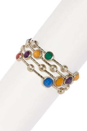 The zirconmania Bracelet Multi-Wire Gold and Beads Bangle 22B0241A showcases round red, purple, green, blue, and orange gemstones with textured gold beads, elegantly displayed on a white cylindrical stand.