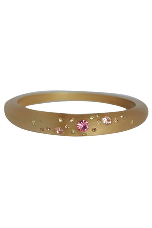 The zirconmania Bracelet Jeweled frosted slender bangle 629B364 features a matte gold finish with small pink and yellow gemstones of assorted sizes, set asymmetrically for an elegant, jeweled look.