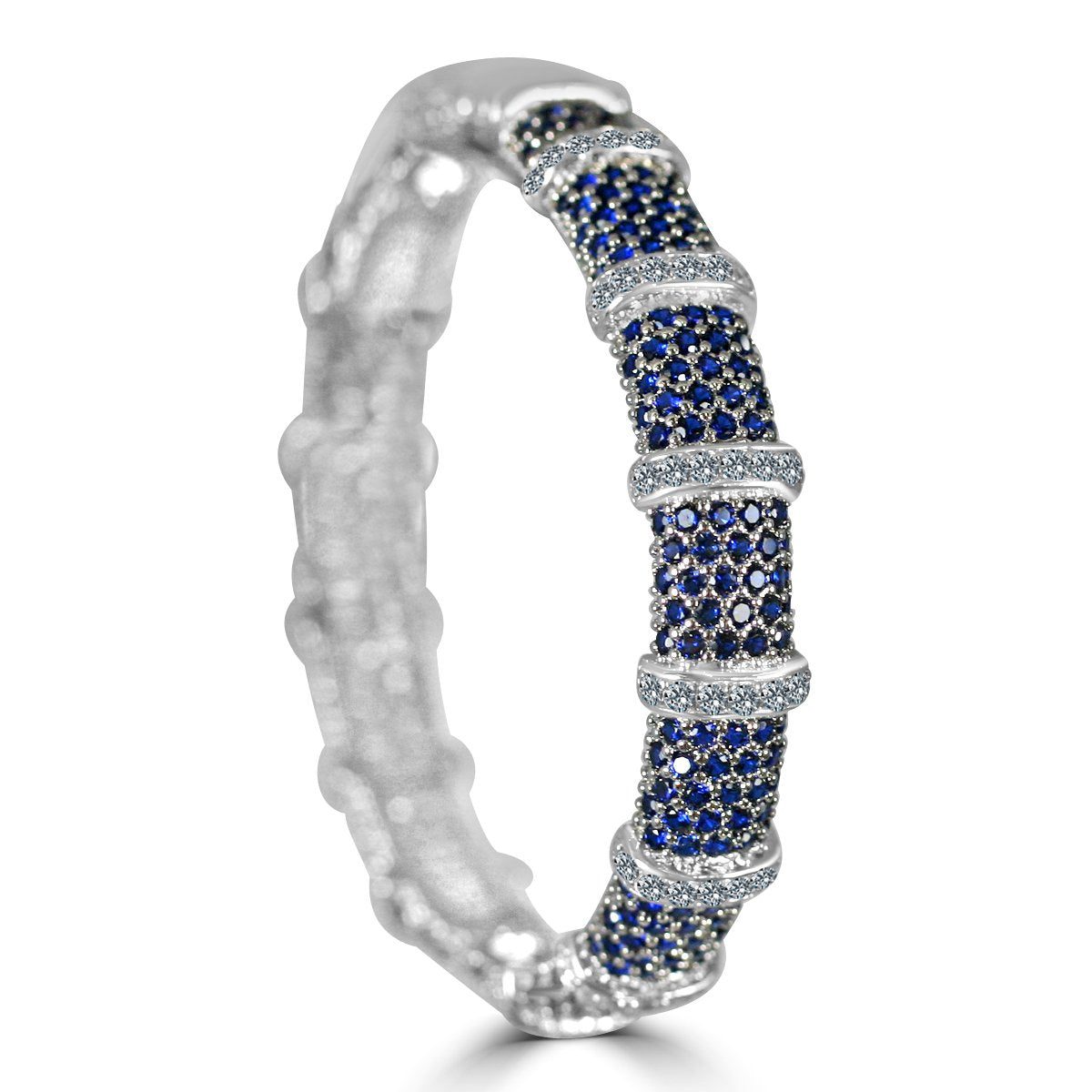 The zirconmania Bracelet Face-off Line Stations Hinged Bangle 698B100 features wide alternating bands of fine blue and clear cubic zirconia, with cluster-set blue stones separated by rows of sparkling clear stones.