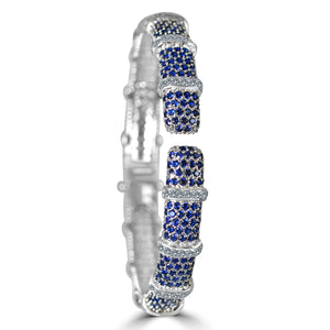 The zirconmania Bracelet Face-off line Stations wide fine Cubic Zirconia Set Hinged Bangle 698B100 features a silver finish with alternating blue and white cubic zirconia sections, textured bands, and intricate detailing for a sparkling segmented look.
