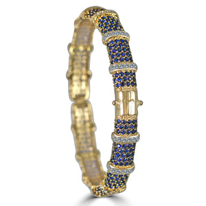 The zirconmania Bracelet Face-off line Stations wide fine Cubic Zirconia Set Hinged Bangle 698B100 features alternating blue and clear cubic zirconia in a bold patterned design, with a seamlessly integrated clasp.