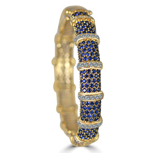 The zirconmania Bracelet Face-off line Stations wide fine Cubic Zirconia Set Hinged Bangle 698B100 features clusters of small blue and white stones, with raised gold bands dividing the blue segments.