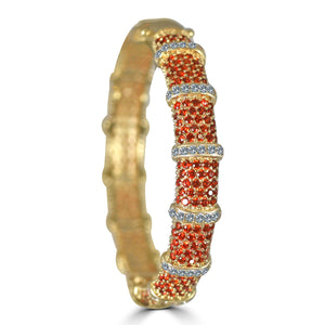 The zirconmania Bracelet Face-off Line Stations Wide Fine Cubic Zirconia Set Hinged Bangle 698B100 features rows of small red stones alternating with clear cubic zirconia for a segmented, textured design around the gold bangle.