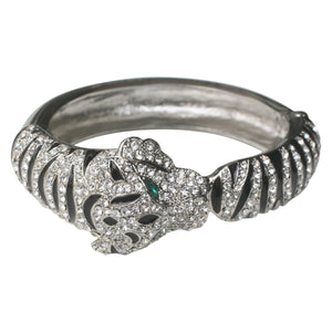 The zirconmania Tiger Stripes Rhodium Bangle 623B3711 features a tiger’s head and paw design with sparkling white crystals and green eye accents.