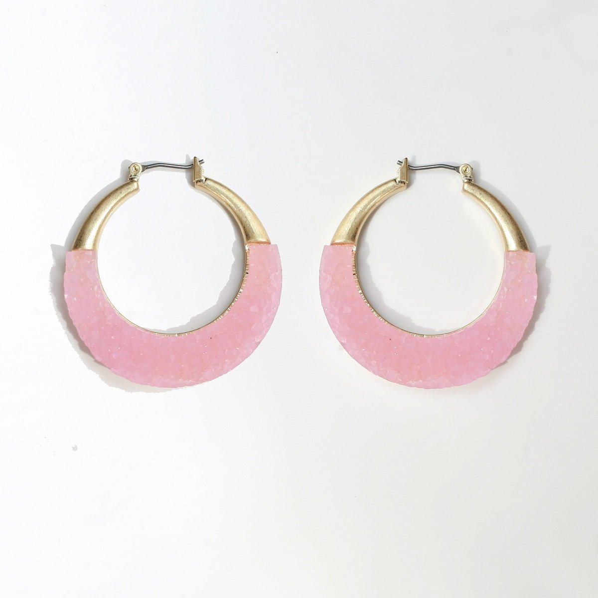 The zirconmania Textured Satin Bezel Alloy Setting Hoop Earrings (661E581) feature gold-tone tops and light pink, textured curved bottoms with hinged saddle closure posts, shown on a plain white background.